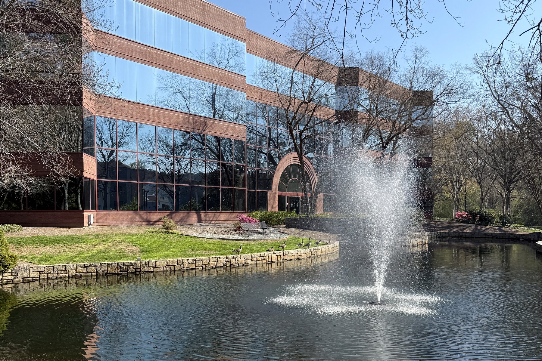 NWX Capital Group building facade with lake and fountain.